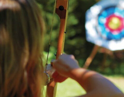 Participant aiming at archery target with group at Cornwall Segway